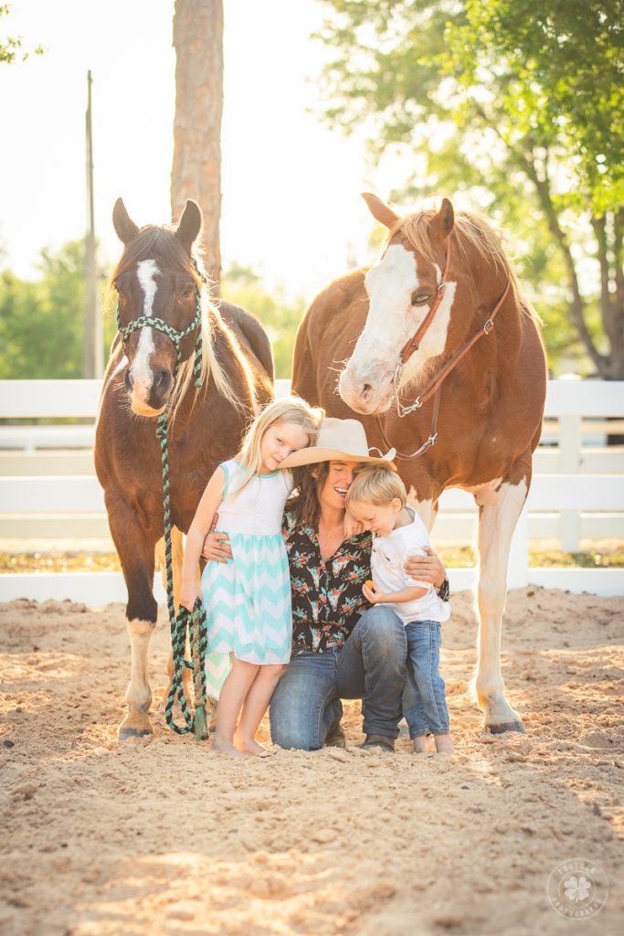 Family photograph of a mom with her two kids posing between two horses in Loxahatchee, Florida. 