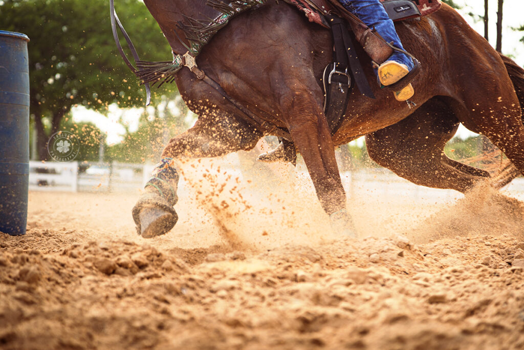 Closeup of a horse's legs as they run around a barrel.  