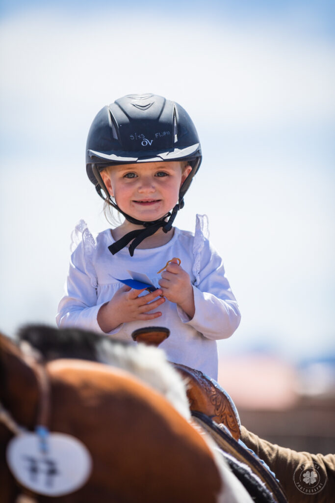 Photograph of a little girl holding a ribbon to her chest while riding a horse in El Paso, Texas. 