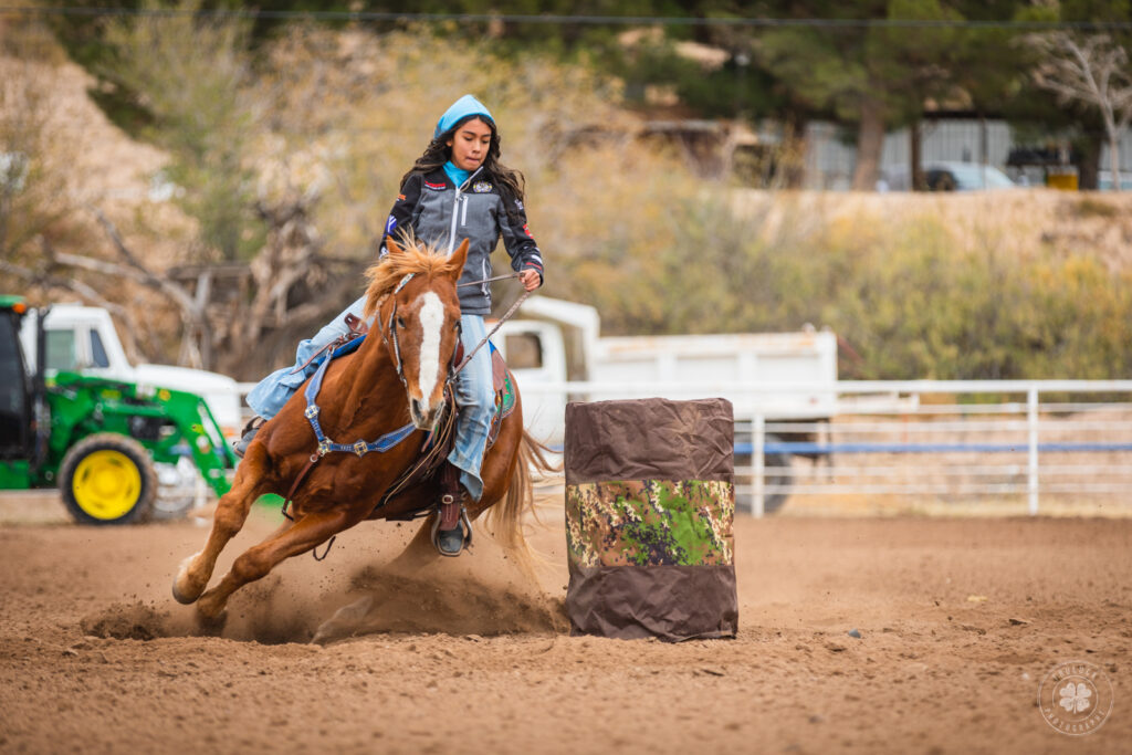 Photograph of a girl riding a horse in a barrel race in El Paso, Texas during a horse show.  