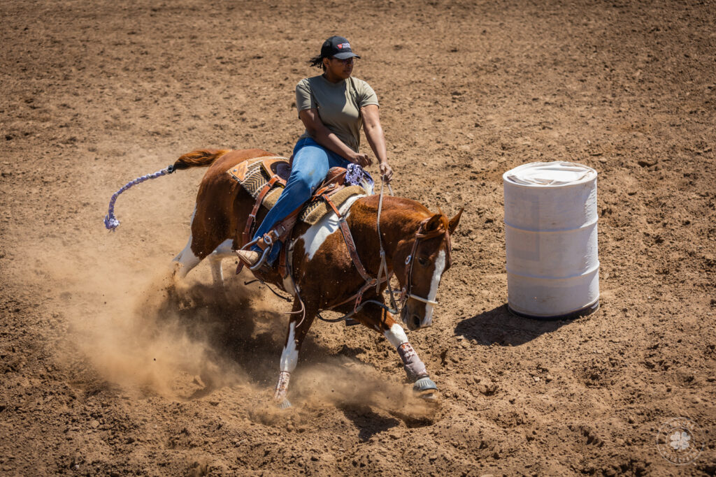 Photograph of a cowgirl riding a horse around a barrel in El Paso, Texas. 