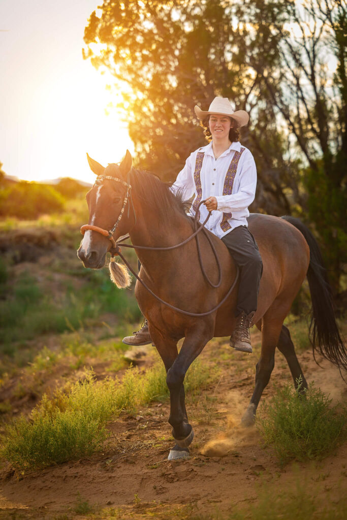 Photograph a a woman riding a brown and black horse bareback through the high desert of Santa Fe. New Mexico. 
