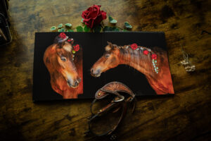 A photograph of an album open on a desk in El Paso, Texas.  It has two pictures of a horse with flowers in his mane against a black background.
