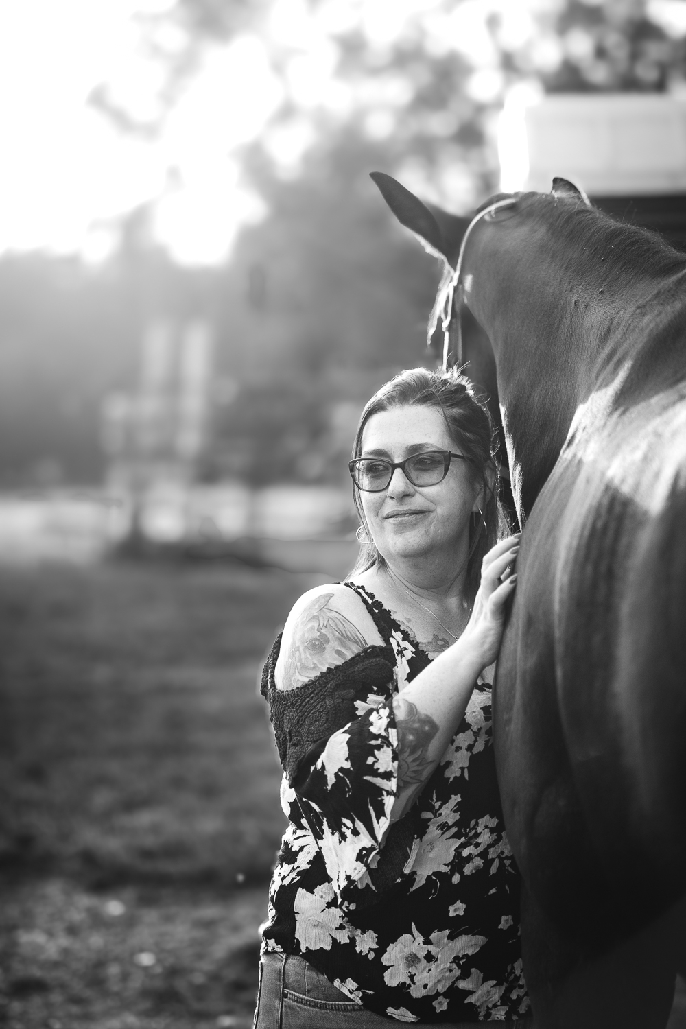 Black and white photograph of a woman leaning onto the shoulder of her horse in Clarksville, Tennessee.