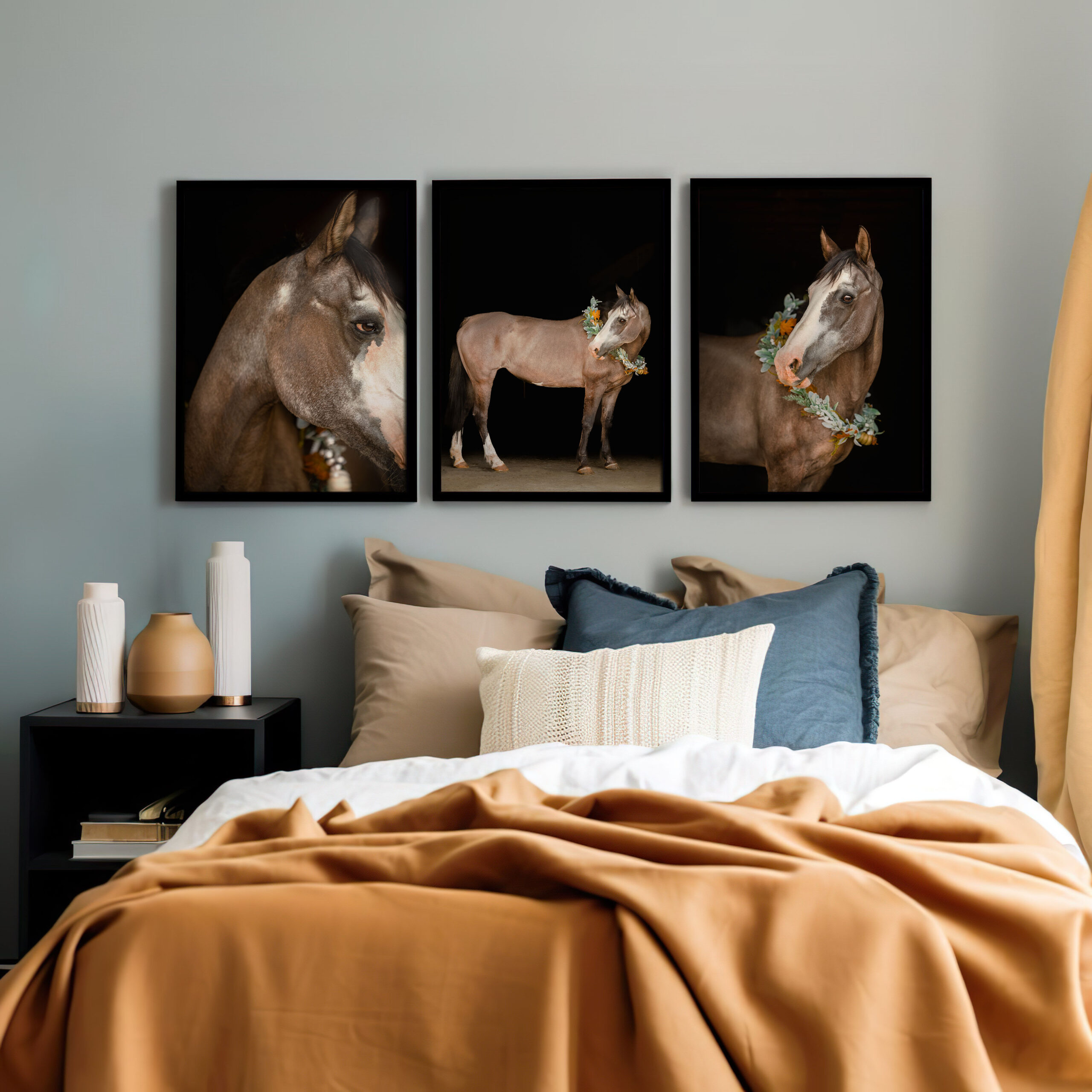 Photograph of a room with orange bedding and a light gray wall featuring three vertical black background photographs of a grulla paint horse in Las Cruces, New Mexico