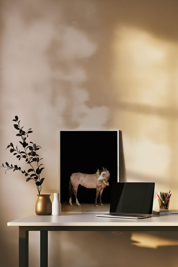 A photograph of an office space with a large print of the black background image framed, sitting behind a laptop.  
